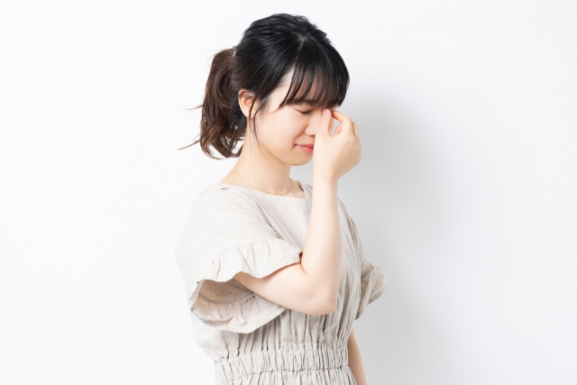 疲れ目を癒すように手で眉間を挟む女性